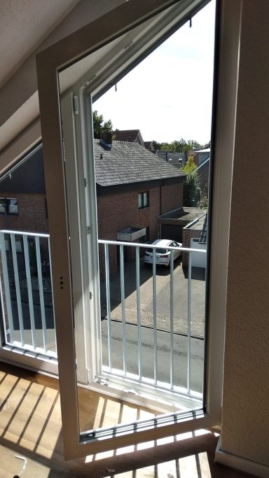 Vor und Nachher Ein offenes Fenster mit Blick auf einen Balkon und angrenzende Gebäude im Freien.